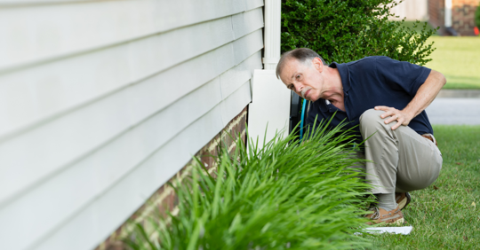 homeowner inspecting around their home’s foundation